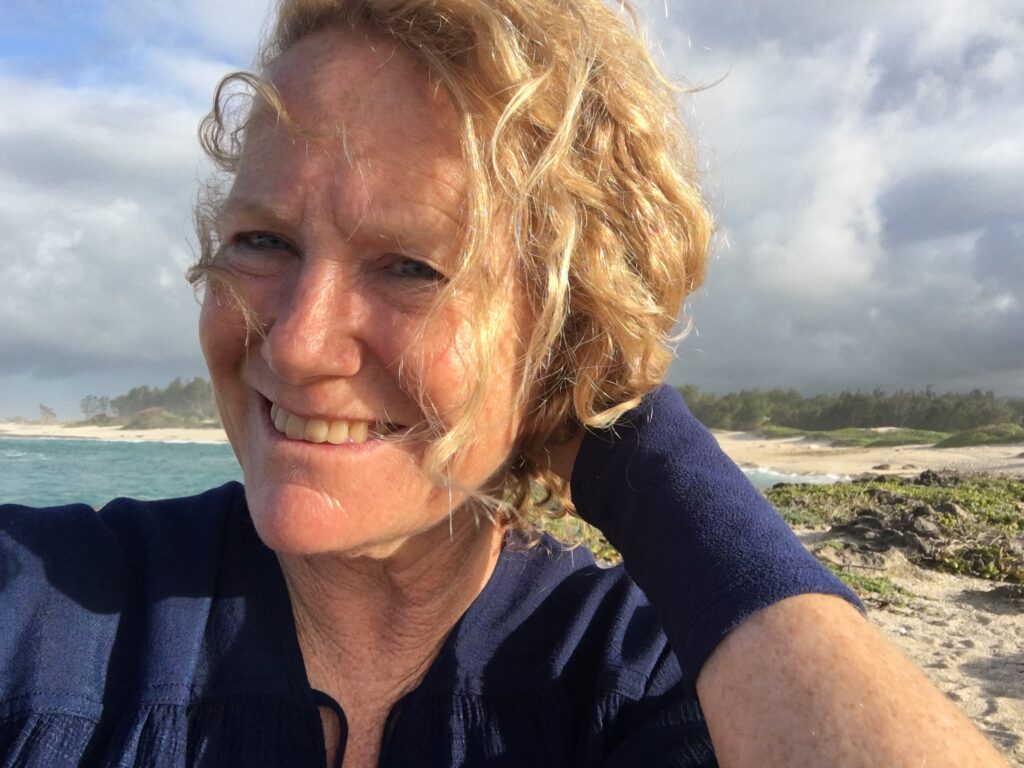 About opis designs dr keri rbown on the beach of HI with blue wrist warmers on 